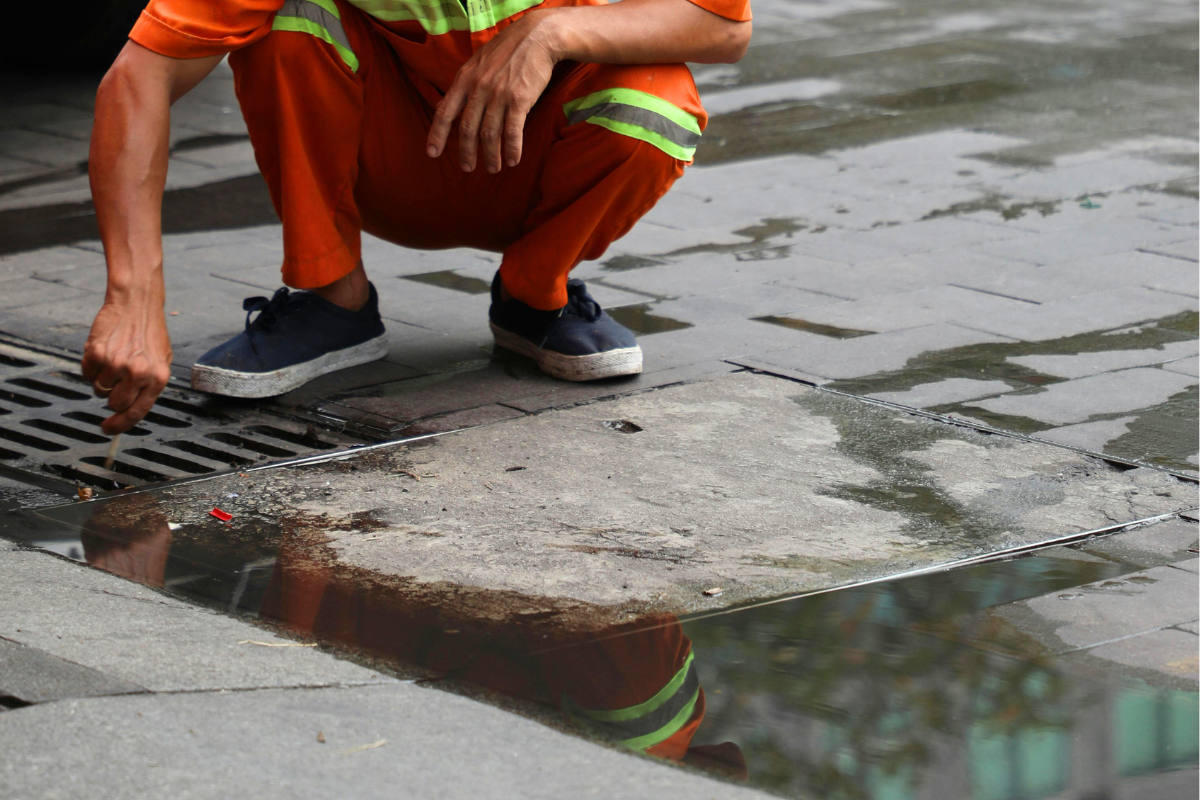 Person performing maintenance checks on public drainage system.