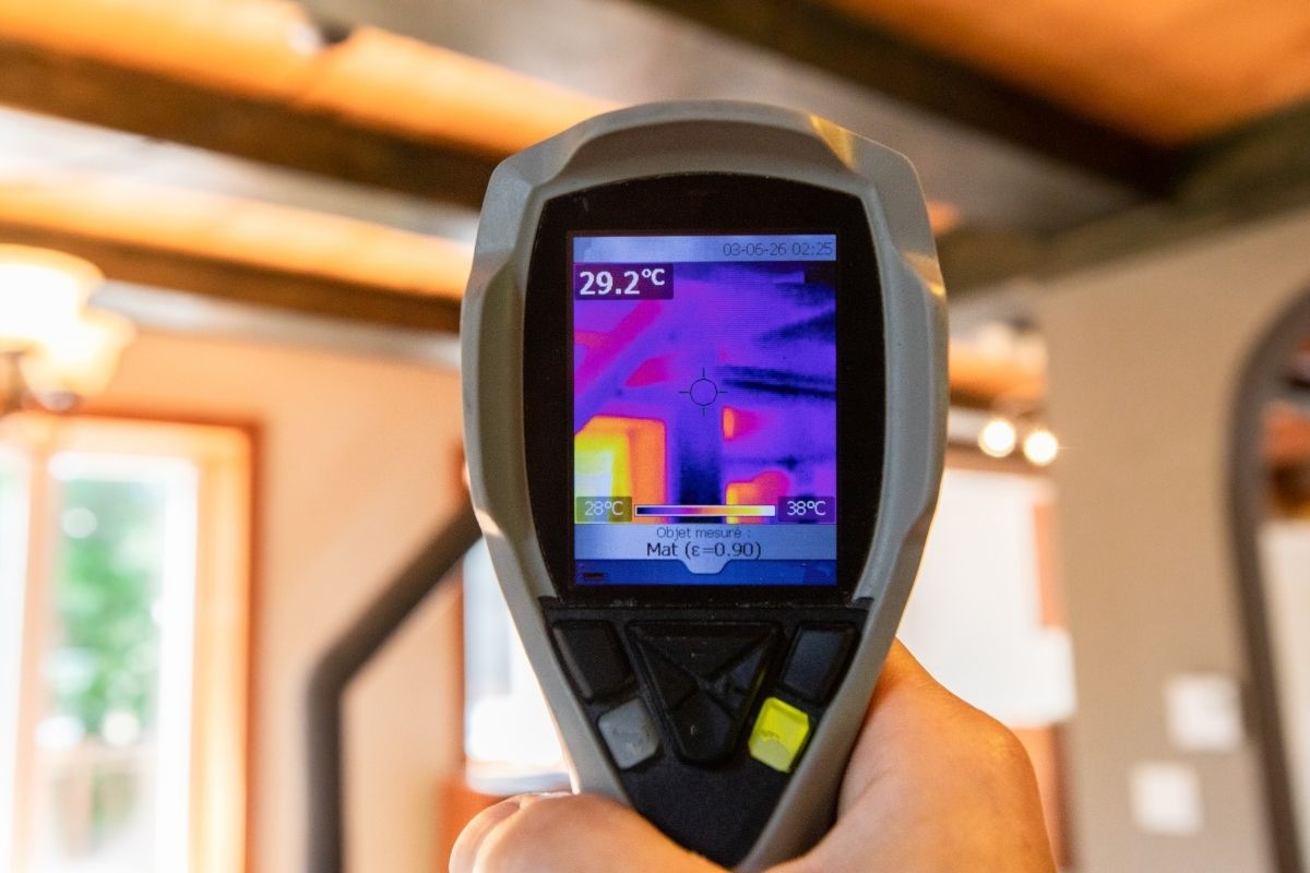 An extreme close-up of the rear LCD screen of a thermal imaging spot camera, showing hot and cold areas inside an office during an environmental quality checkup for Indoor Air Quality (IAQ).