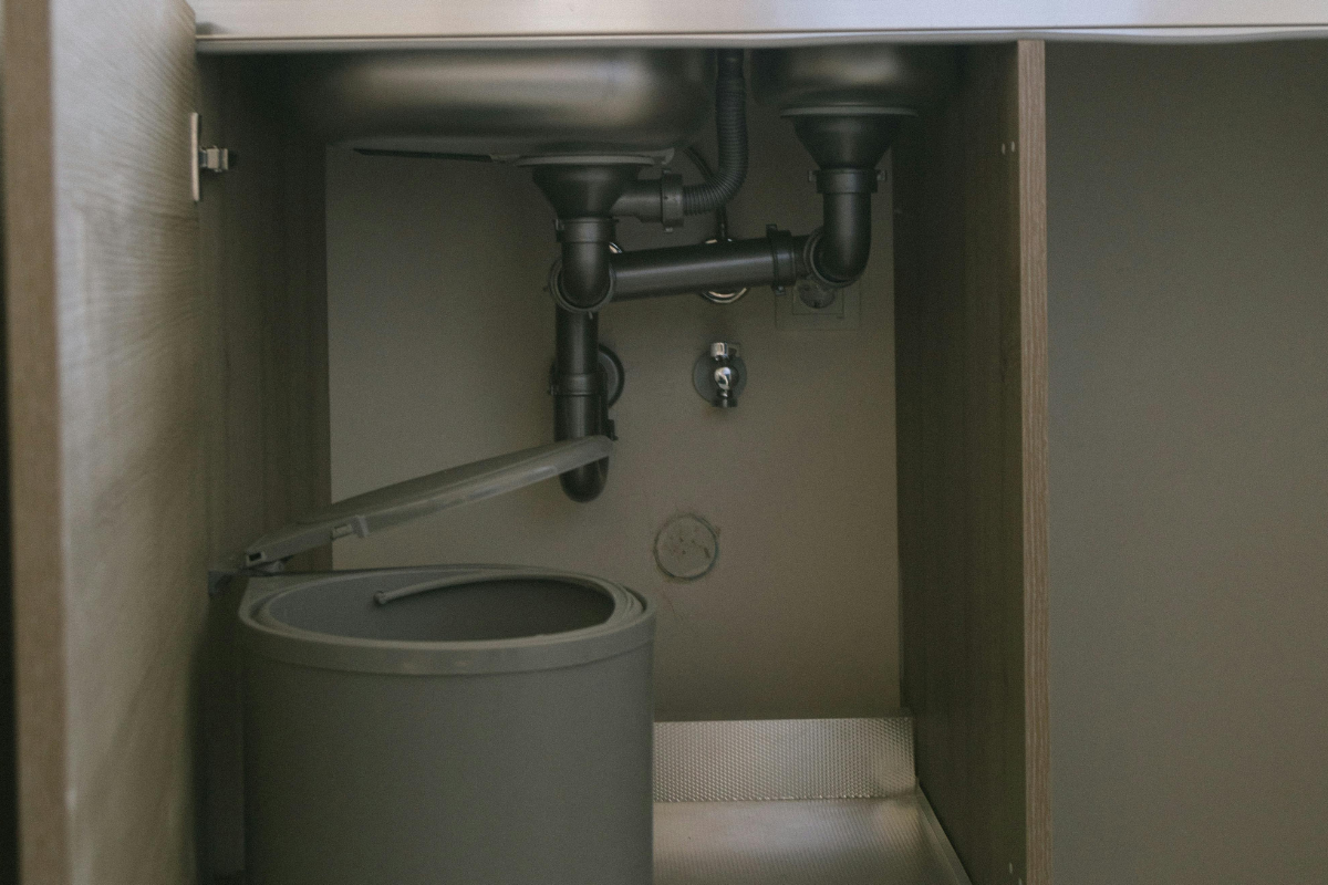 Water pipes under a domestic tap.