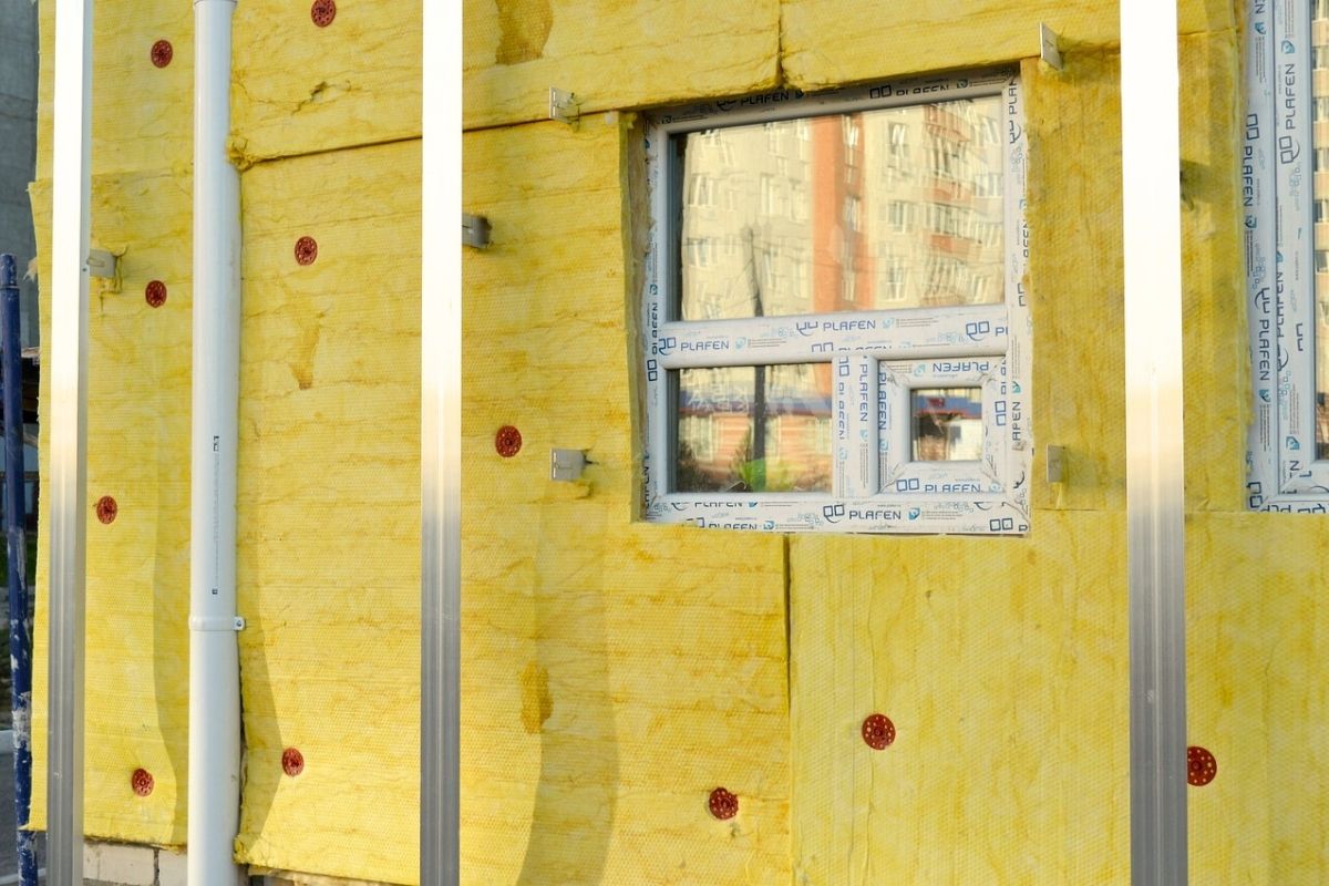 Insulation installation on a commercial building’s exterior, demonstrating effective measures for preventing thermal bridging and improving energy performance. Exterior view of insulation installation on a commercial building, aimed at reducing thermal bridging and improving energy efficiency.