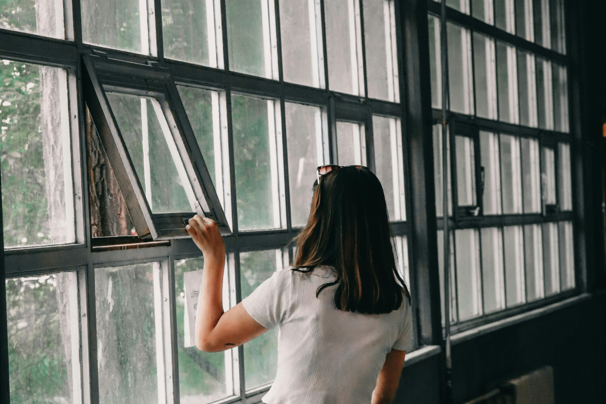 Person opening a window in a building to ventilate.
